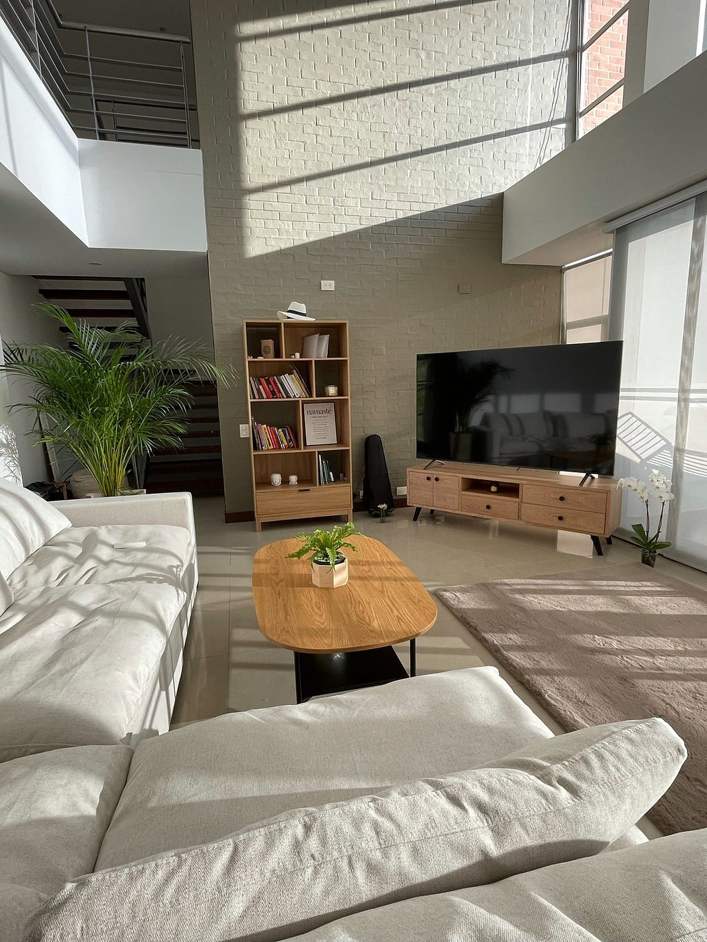 Sala de doble altura del proyecto Solaris con muro de ladrillo blanco y luz natural