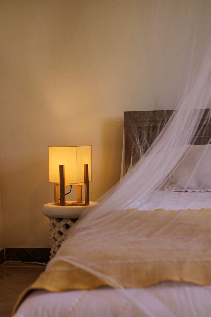 Detalle de mesa de noche y lámpara de madera junto a la cama en Casa Taná