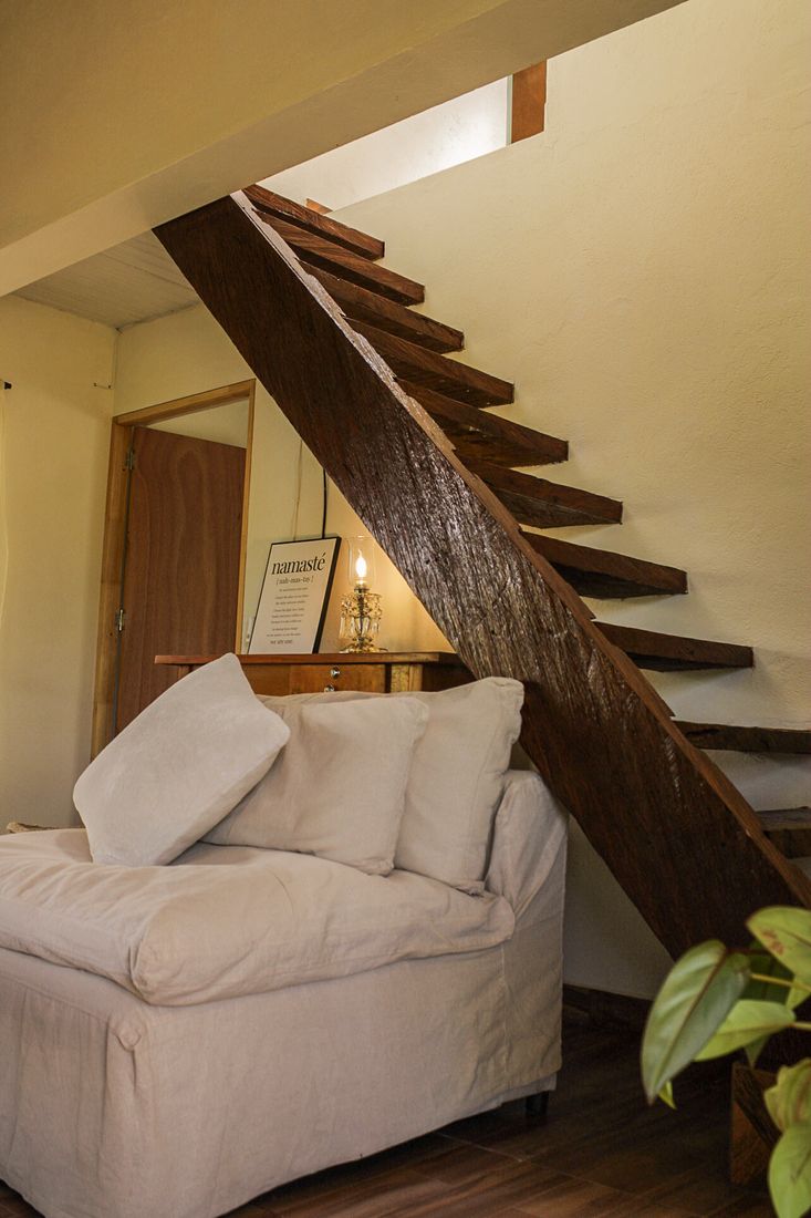 Rincón de lectura bajo la escalera de madera en Casa Taná